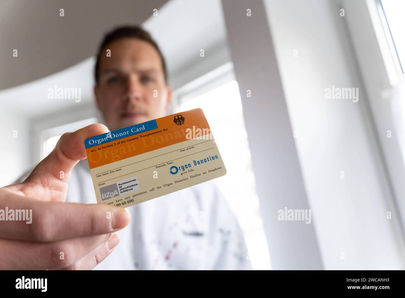 Augusta, Baviera, Germania - 14 gennaio 2024: Il giovane ha in mano una tessera donatrice di organi *** Junger Mann hält einen Organspendeausweis in der Hand Foto Stock