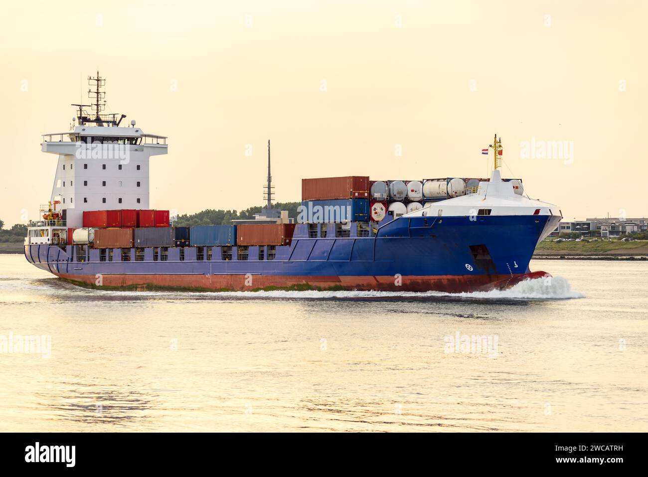 Nave portacontainer che arriva in un porto al tramonto in estate Foto Stock