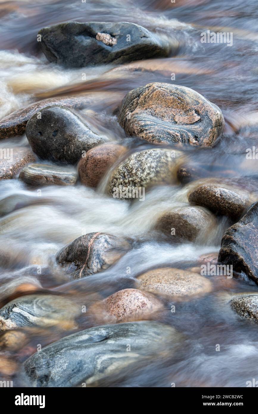 Acqua che scorre velocemente sulle rocce. River Findhorn, Morayshire, Scozia. Esposizione lunga astratta Foto Stock