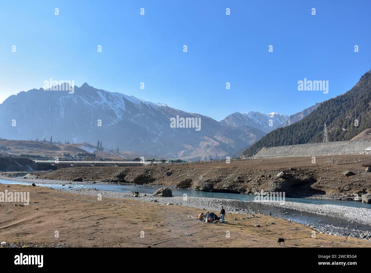 I visitatori si rilassano in un campo asciutto e senza neve durante una giornata invernale soleggiata nella stazione di Sonamarg Hill, a circa 100 km da Srinagar. Un lungo periodo di secchezza si sta diffondendo attraverso la valle del Kashmir durante la fase più dura dell'inverno. Località turistiche come Gulmarg, Pahalgam e Sonamarg avrebbero in genere accumulato un'ampia neve ormai. Ma quest'anno, la valle del Kashmir è asciutta, senza neve da nessuna parte. Mentre il settore turistico è stato colpito duramente, mentre i turisti, che avevano programmato di visitare la Valle a gennaio per godersi la neve, stanno cancellando i loro viaggi. Foto Stock