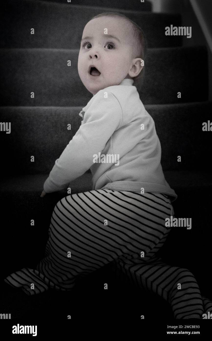 Bambino piccolo, bambino piccolo, scalare le scale in pigiama a righe, catturato in un riflettore in un blu freddo e tenue, che fa una fuga. Foto Stock