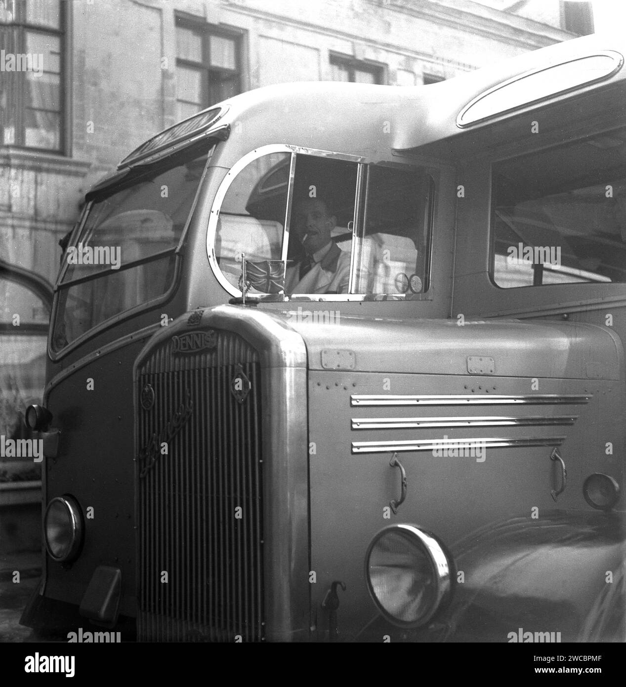 1950, vista storica della calandra e della cabina con autista di un pullman o autobus Dennis, Dennis Lancet III con carrozzeria Duple, Bruxelles, Belgio. Sul cofano è presente un martinetto di raccordo, con logo RAC e TCS sulla griglia. Foto Stock