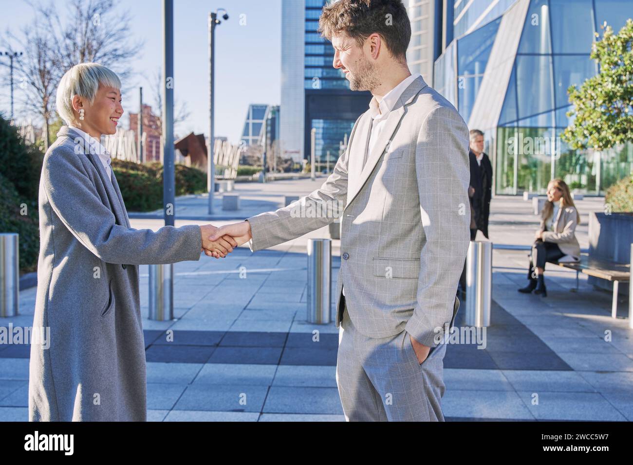 donna d'affari asiatica con i capelli bianchi che chiude un accordo con un giovane uomo d'affari in un completo stringendo la mano. concetto aziendale Foto Stock