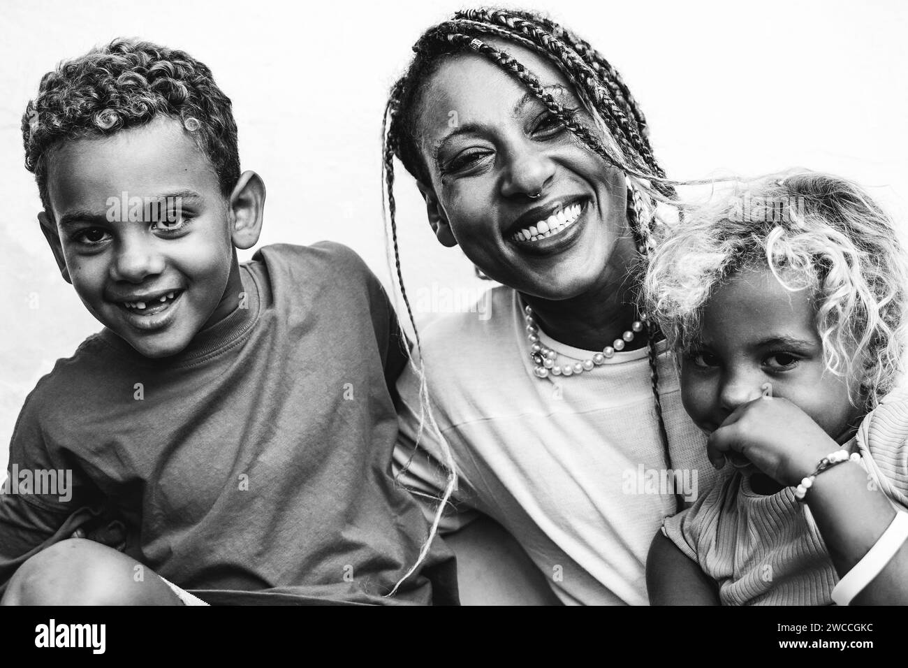 La famiglia africana si diverte all'aperto. Madre, figlia e figlio che ridono. Rapporto di famiglia, editing in bianco e nero Foto Stock