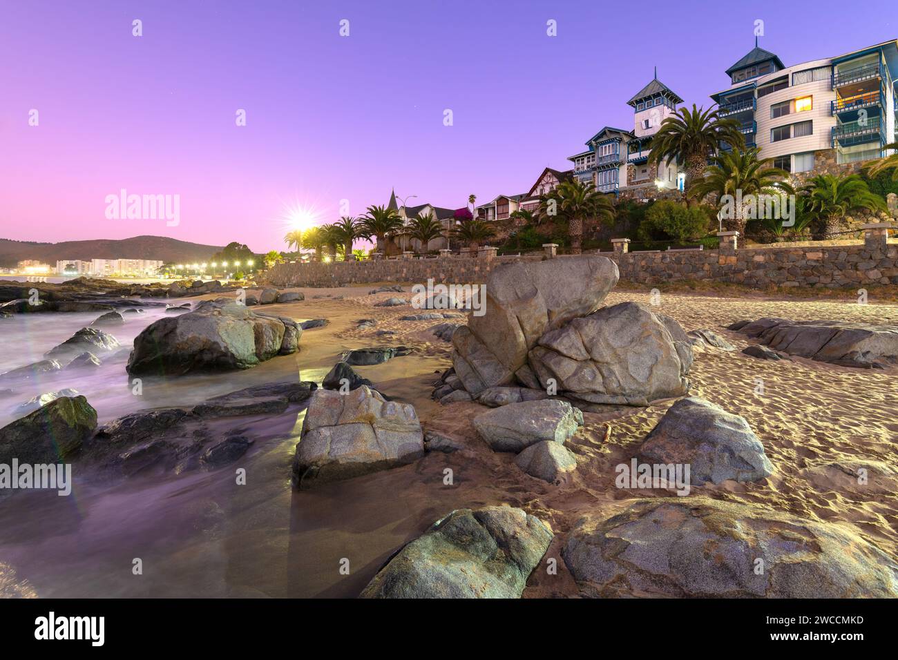Il tramonto si adagia sulla pittoresca cittadina di mare di Papudo, che getta un sereno bagliore viola sulla costa rocciosa, mettendo in risalto la sua affascinante architettura costiera, Foto Stock
