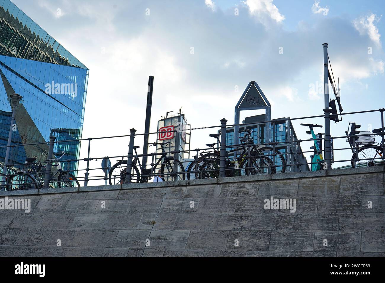 Biciclette parcheggiate su una ringhiera di fronte alla stazione centrale di Berlino e all'edificio 3XN Cube a Berlino, Germania Foto Stock
