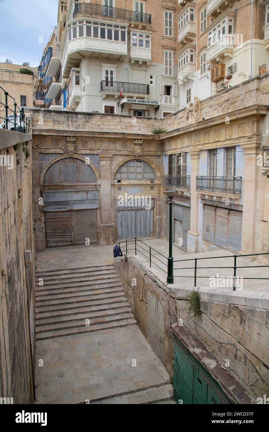 Una moltitudine di finestre e una serie di scale che conducono al suo livello inferiore a Valletta, Malta Foto Stock