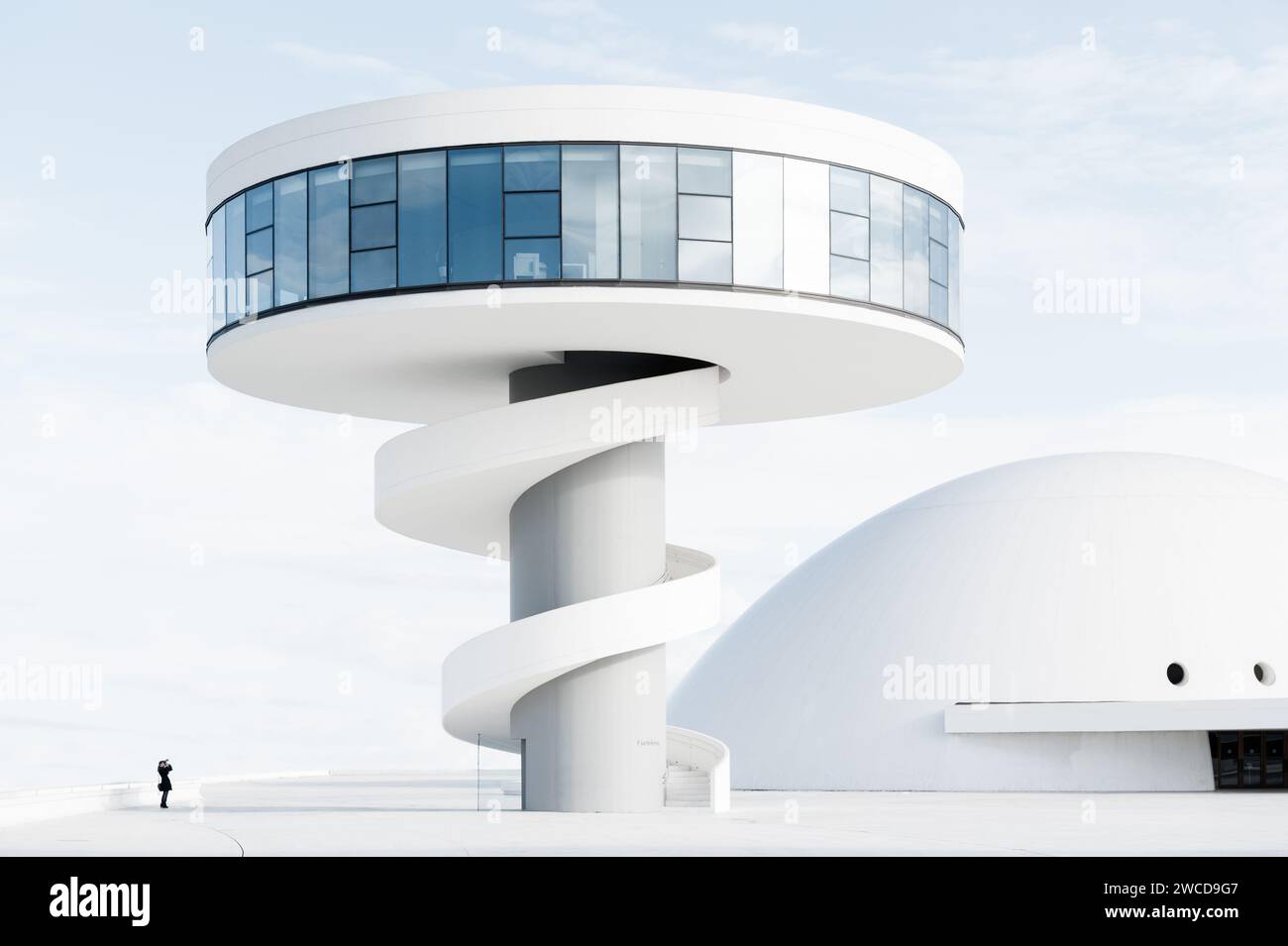 Persona in piccolo che fotografa la torre e il centro espositivo del Niemeyer Center di Aviles, Asturie, Spagna. Foto Stock