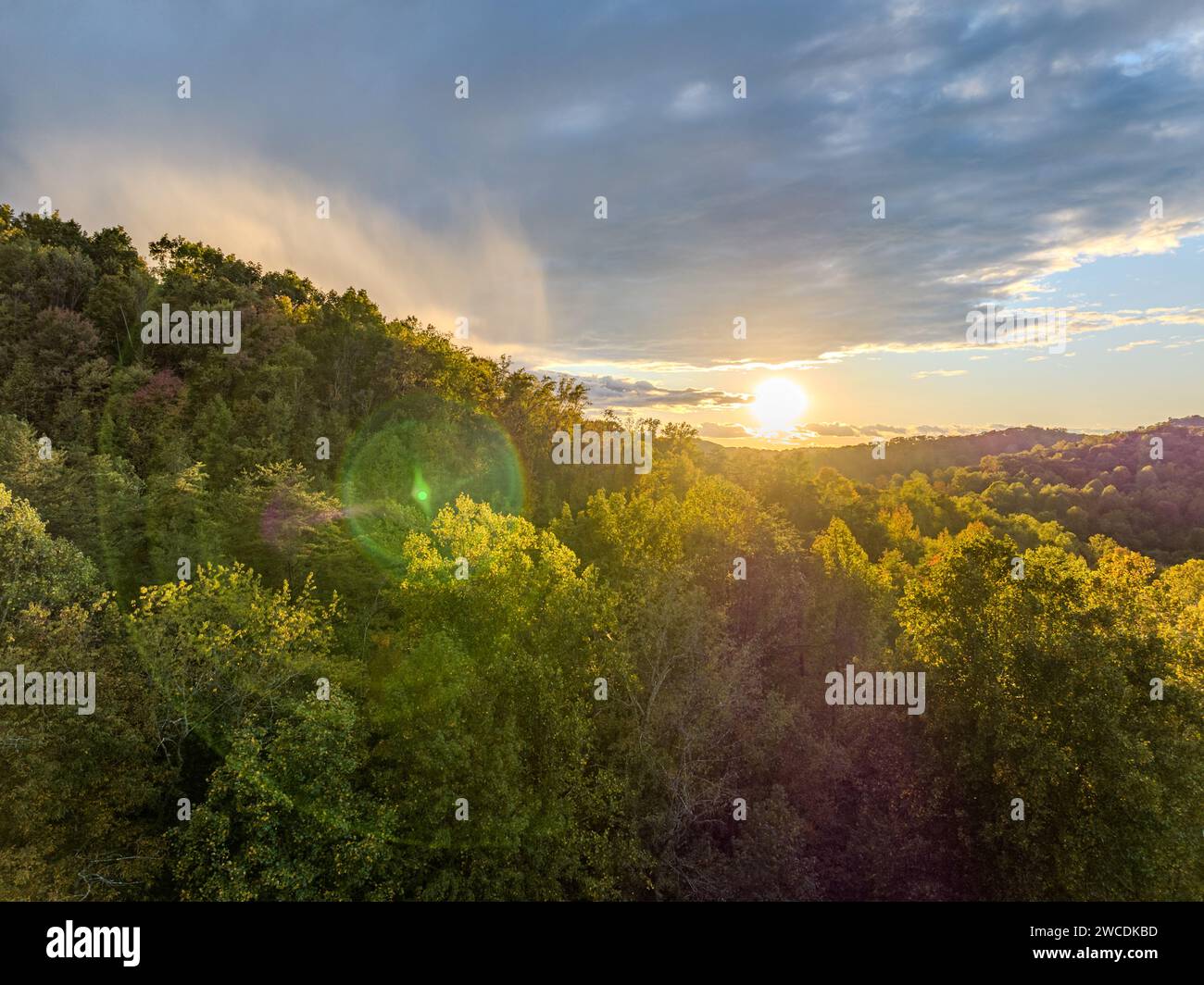 Il sole tramonta sul paesaggio boscoso della Coopers Rock State Forest, con raggi che si infrangono tra le nuvole Foto Stock