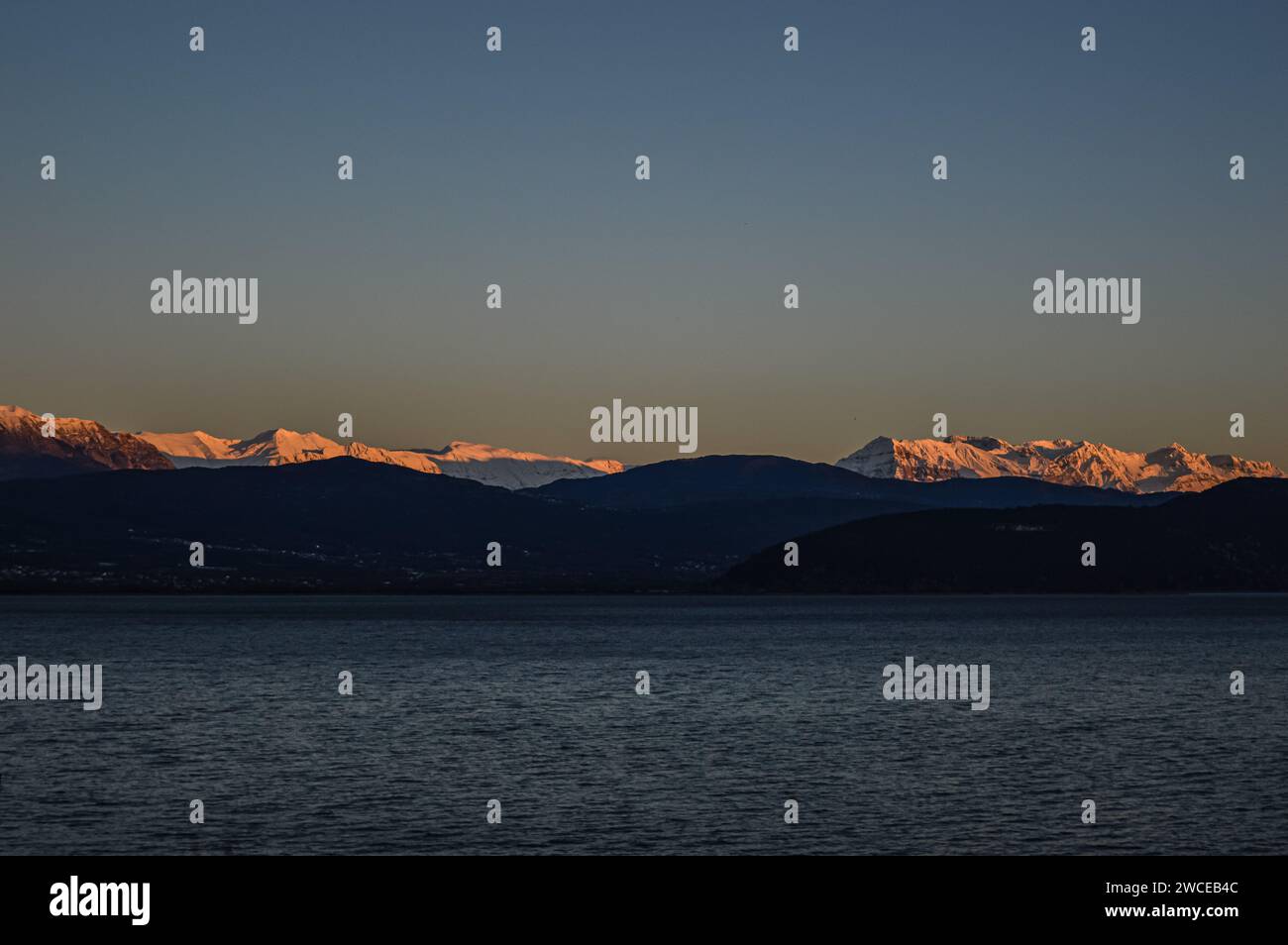 Riflesso del tramonto sulle montagne sopra un lago. Foto Stock