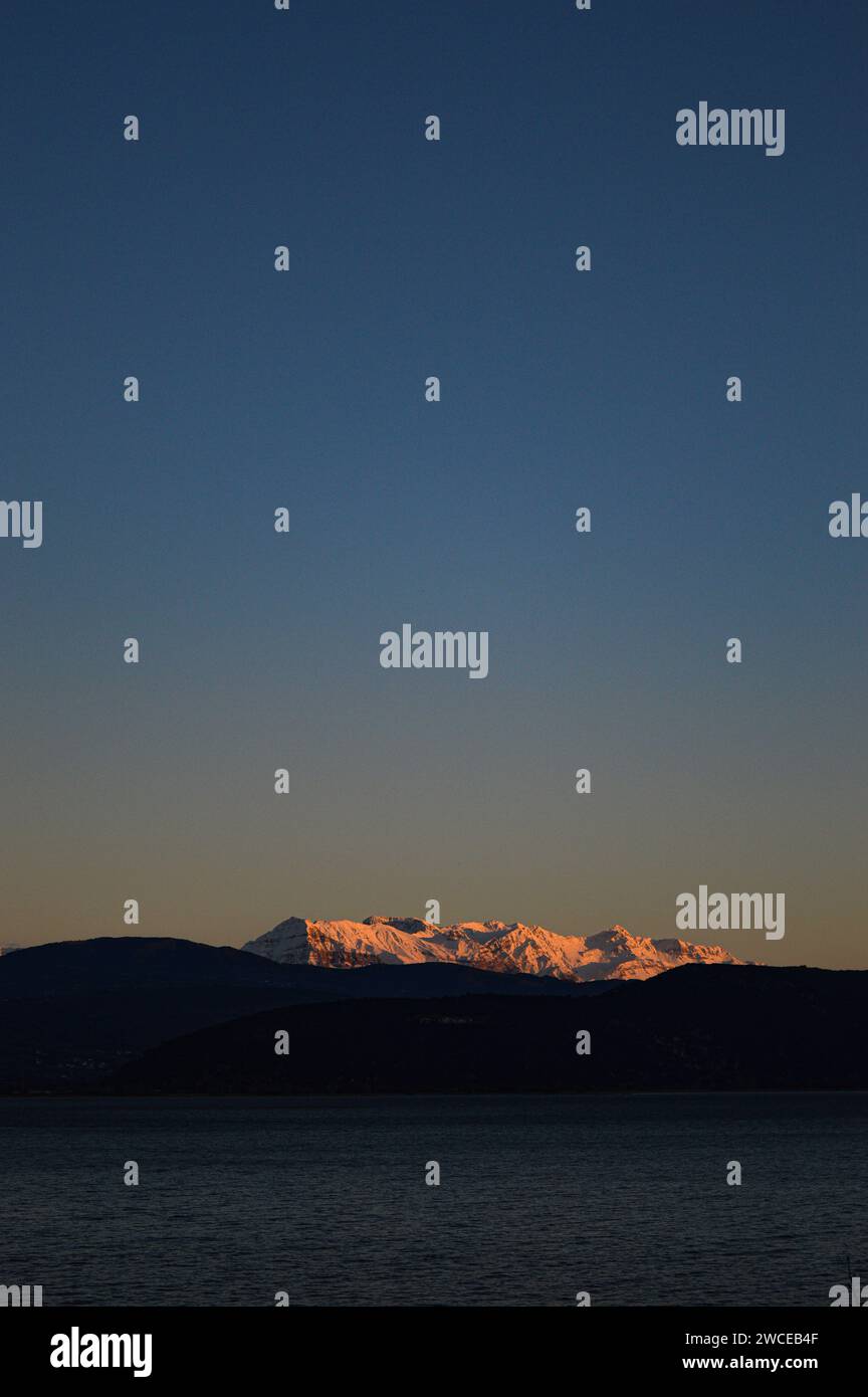 Riflesso del tramonto sulle montagne sopra un lago. Foto Stock