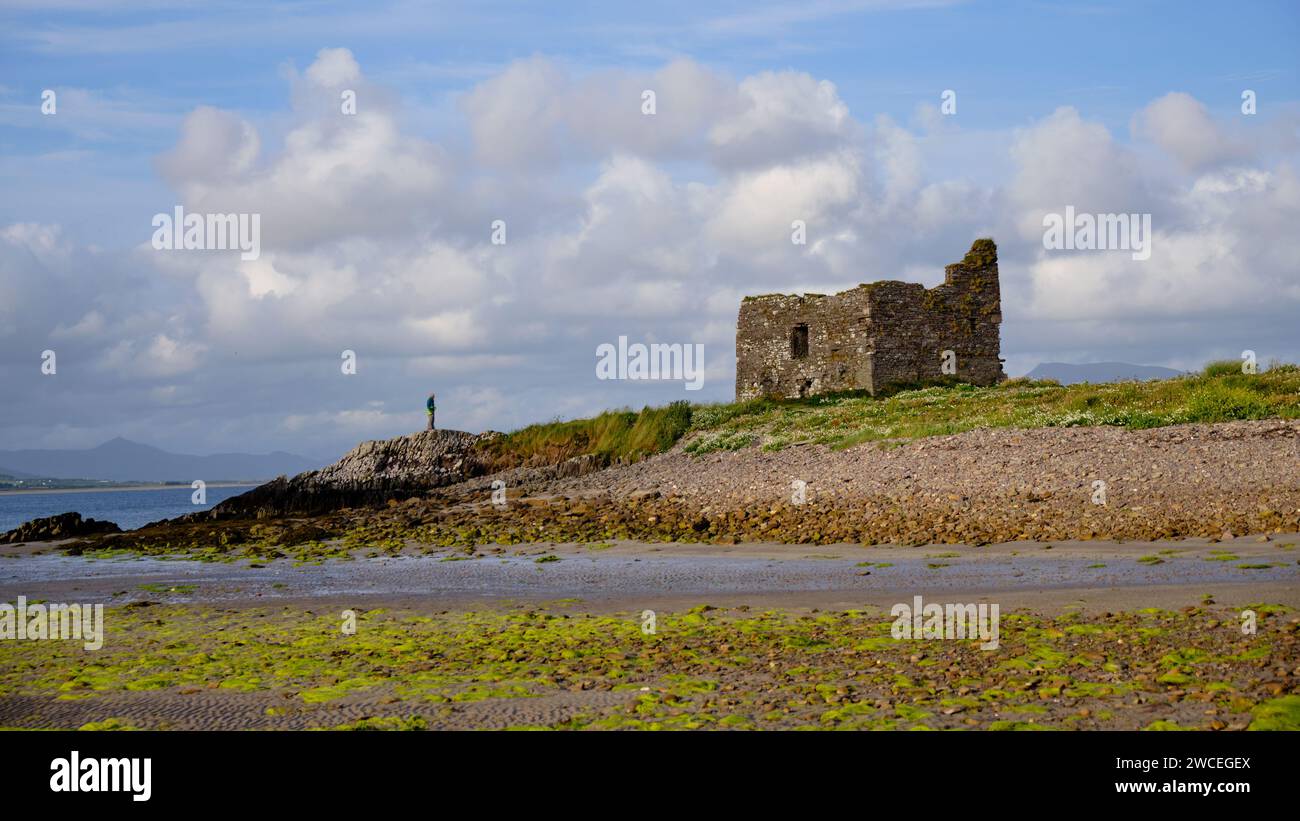 McCarthy Mor Casa Torre Ballinskelligs Castello con figura solitaria in piedi vicino. Baile un Sceilg, nella contea di Kerry, Irlanda Foto Stock