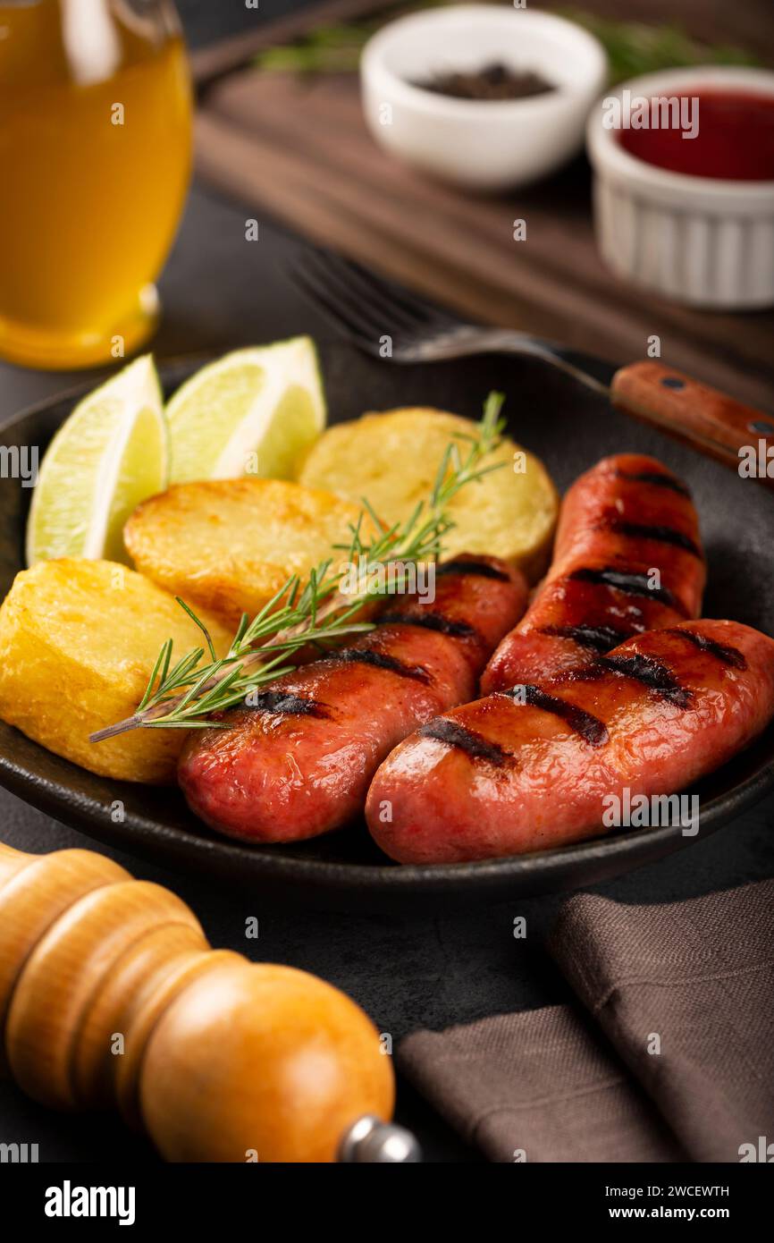 Salsicce grigliate con barbecue su sfondo di legno. Foto Stock