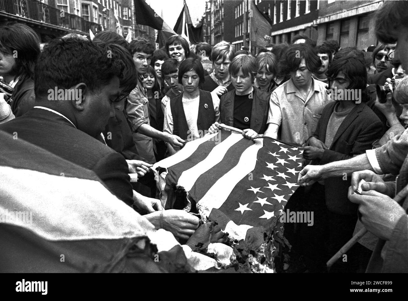 Manifestanti in Grosvenor Street a Londra che tentano di bruciare una bandiera americana vicino all'ambasciata degli Stati Uniti in Grosvenor Square durante la marcia di protesta anti-Vietnam del 17 marzo 1968 . A causa del violento scontro tra manifestanti e polizia, questa massiccia protesta divenne nota come "la battaglia di Grosvenor Square" e fu l'ispirazione per la canzone dei Rolling Stones, "Street Fighting Man". Foto Stock