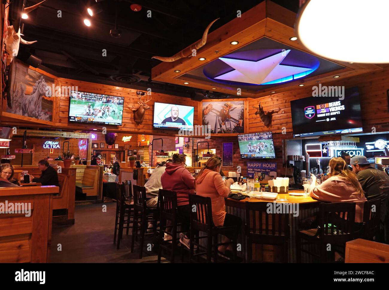I clienti si siedono in un bar e guardano gli sport in un ristorante Texas Roadhouse - novembre 2023 Foto Stock