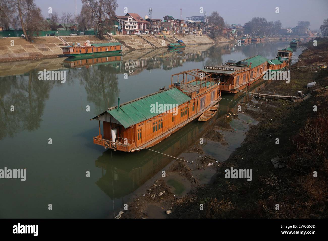 Srinagar, India. 15 gennaio 2024. 15 gennaio 2024, Srinagar Kashmir, India: Le case galleggianti sono viste sulle rive del fiume Jhelum a Srinagar. Un lungo periodo invernale secco lascia il fiume Jhelum a Historic Low, mettendo a rischio le case galleggianti e deludenti sciatori a Gulmarg. Il 15 gennaio 2024, Srinagar Kashmir, India. (Foto di Firdous Nazir/Eyepix Group) credito: SIPA USA/Alamy Live News Foto Stock