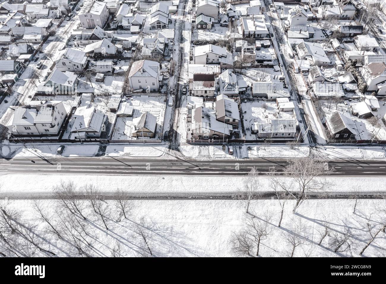 periferia di una zona residenziale coperta dalla neve in una fredda e soleggiata giornata invernale. vista aerea dall'alto. Foto Stock