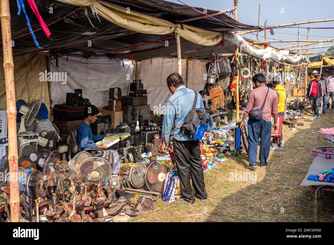 Jaynagar, India. 15 gennaio 2024. Un'ampia panoramica dei negozi di materiali di scarto e di prodotti usati all'interno di una fiera di rottami nel Bengala Occidentale. Gli abitanti di Mathurapur, Bengala Occidentale, India, hanno osservato una migliore pratica di gestione dei rifiuti organizzando una sorta di fiera, la "Bhanga Mela" (Una fiera di articoli di scarto), dove espongono in vendita oggetti usati e abbandonati per la casa. Migliaia di persone vengono qui per acquistare questi rottami o beni usati da utilizzare nelle loro case. Credito: SOPA Images Limited/Alamy Live News Foto Stock