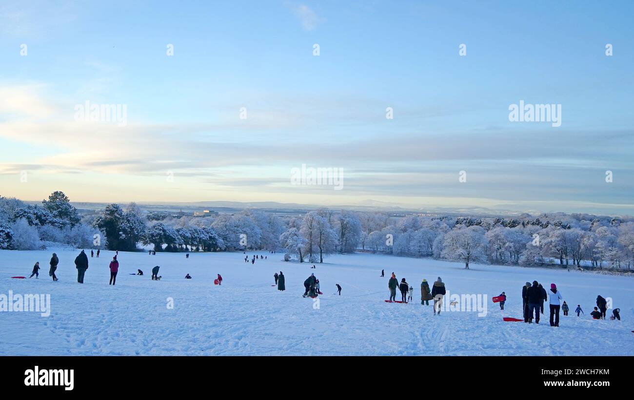 Le persone approfittano del tempo innevato con le slitte a Camp Hill a Woolton, Liverpool. Gran parte della Gran Bretagna sta affrontando un'altra giornata di basse temperature e di interruzioni dei viaggi dopo che i bassi della notte sono scesi sotto il congelamento per la maggior parte del paese. Un "tuffo freddo dell'aria artica” si è spostato a sud in tutto il paese negli ultimi giorni, rendendolo 5C-6C più basso del solito per questo periodo dell'anno, ha detto l'Ufficio MET. Data immagine: Martedì 16 gennaio 2024. Foto Stock