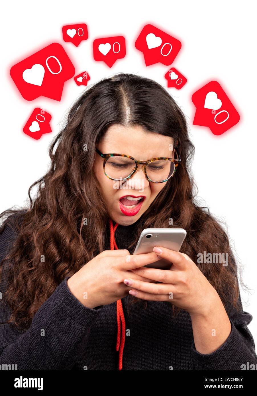 Concetto di inattività nei social network. La ragazza guarda con sorpresa il suo telefono su uno sfondo bianco. Dipendenza dai social media. Rosso brillante come icone. Foto Stock