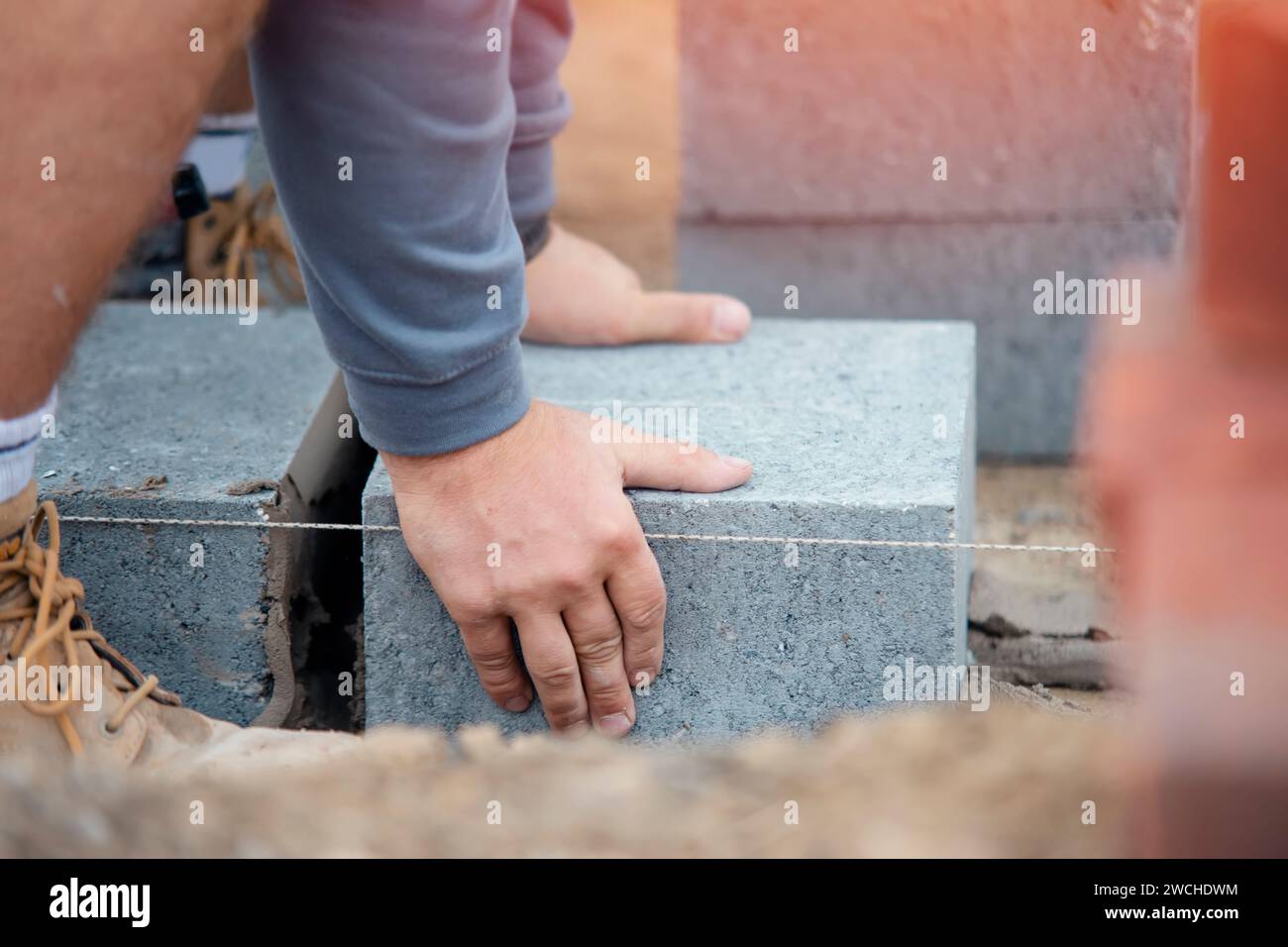 Muratore che posa blocchi di calcestruzzo ad alta densità Foto Stock