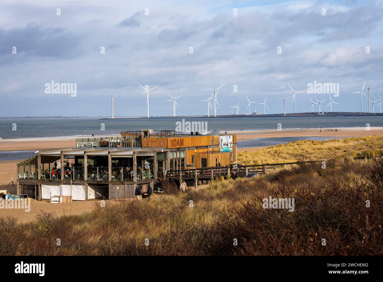 Il padiglione sulla spiaggia De Dam sulla spiaggia di Vrouwenpolder su Walcheren, sullo sfondo delle turbine eoliche presso la barriera della Schelda orientale, Zelanda, Netherl Foto Stock