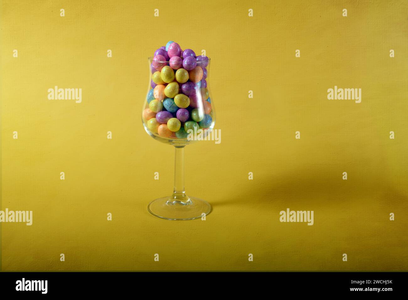 Mini uova di Pasqua in un bicchiere. Spazio di copia su entrambi i lati della foto verticale. Livello texture digitale aggiunto all'immagine. Foto Stock