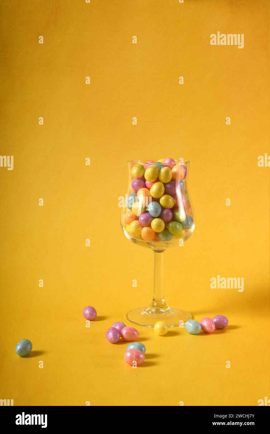 Foto verticale di piccole uova di Pasqua colorate in un bicchiere. Copia spazio. Foto Stock