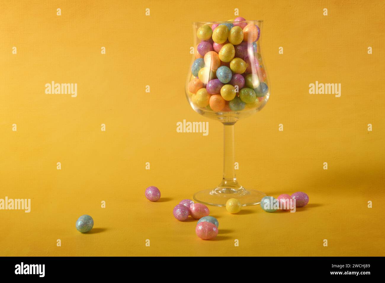 Foto orizzontale di uova di Pasqua dai colori pastello in un bicchiere. Copia spazio a sinistra. Foto Stock