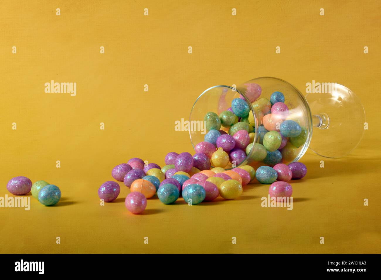 Uova pasquali dai colori pastello versate da un bicchiere. Foto orizzontale con spazio per la copia. Foto Stock