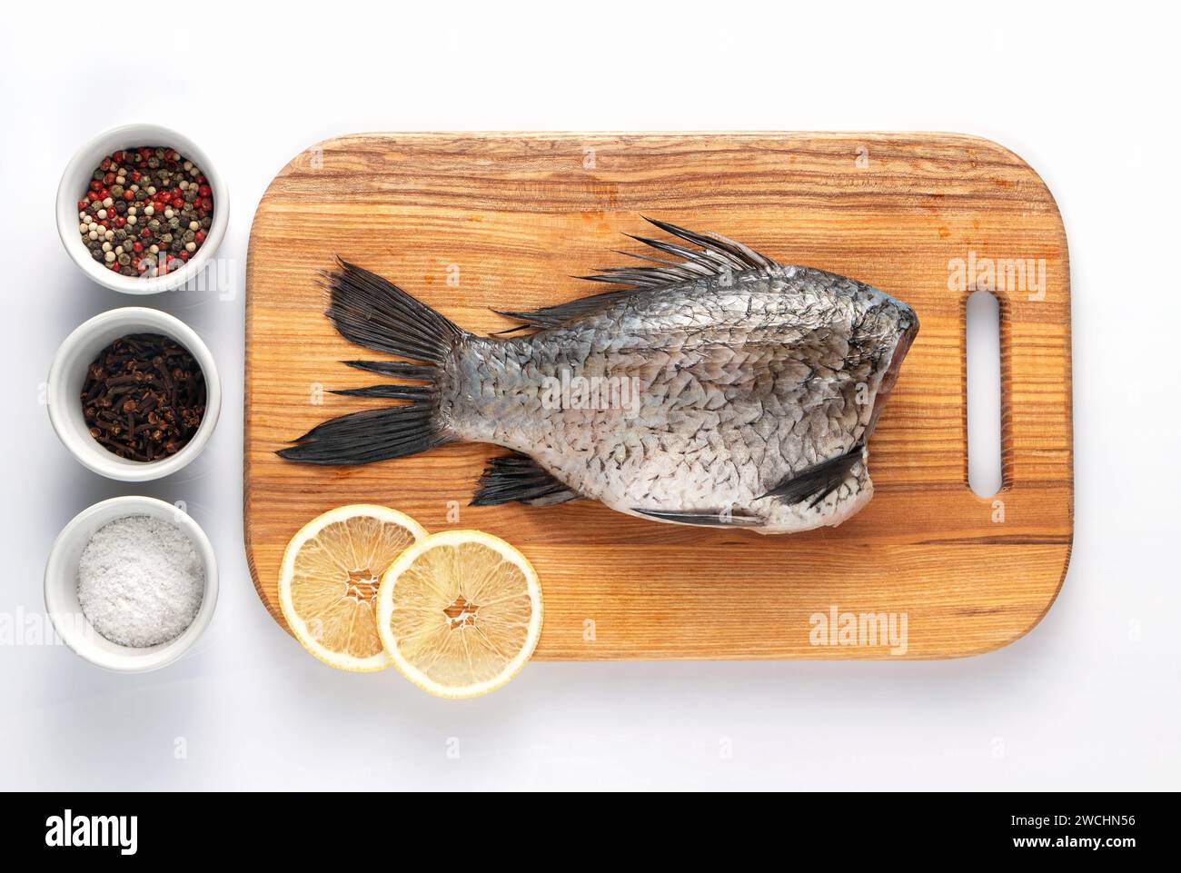Carpa sbucciata su un tagliere con fette di limone e spezie, pronta da cuocere. Cibo sano e dietetico. Foto Stock