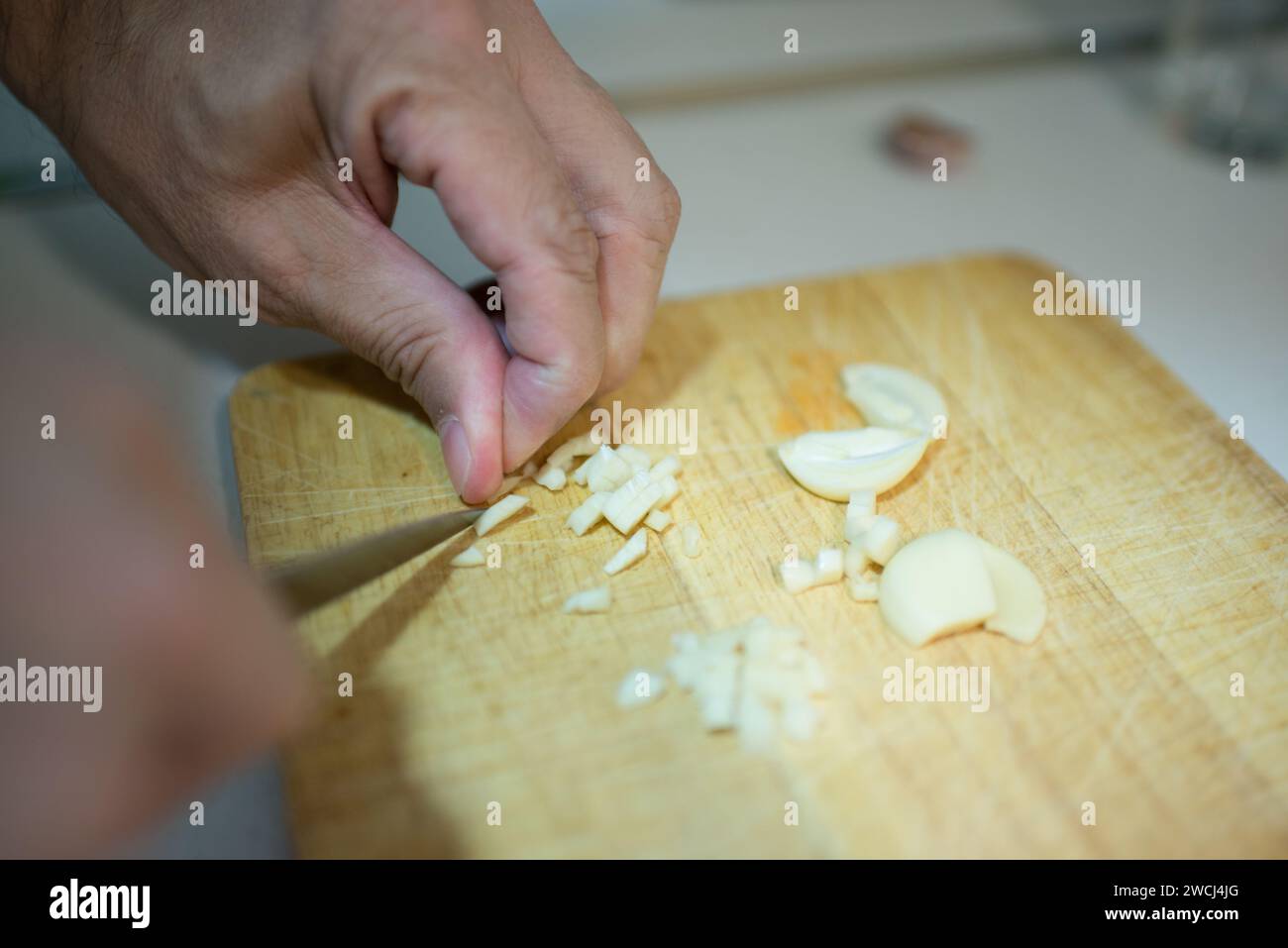 Tagliando a mano i denti dell'aglio in piccoli pezzi. Interni Foto Stock