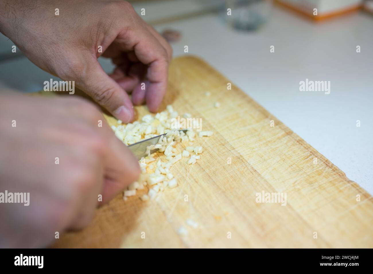Cucina domestica. Primo piano di una persona irriconoscibile che taglia l'aglio Foto Stock