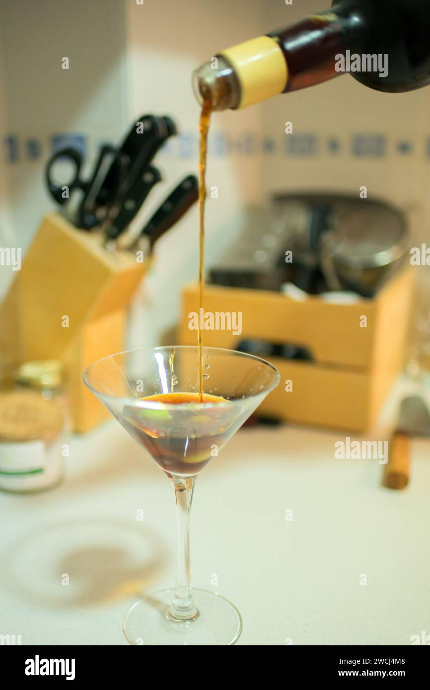 Versare un bicchiere di martini in una cucina domestica. Bicchiere di vetro Foto Stock