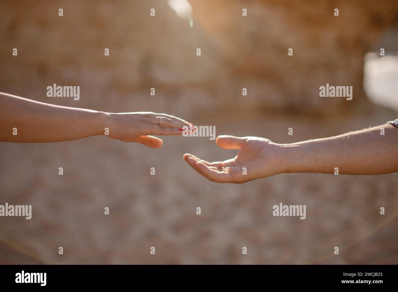 Uomo e donna che si allungano le mani a vicenda sulla spiaggia, Algarve, Portogallo Foto Stock