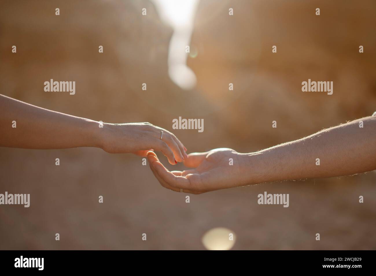 Uomo e donna che si allungano le mani a vicenda sulla spiaggia, Algarve, Portogallo Foto Stock