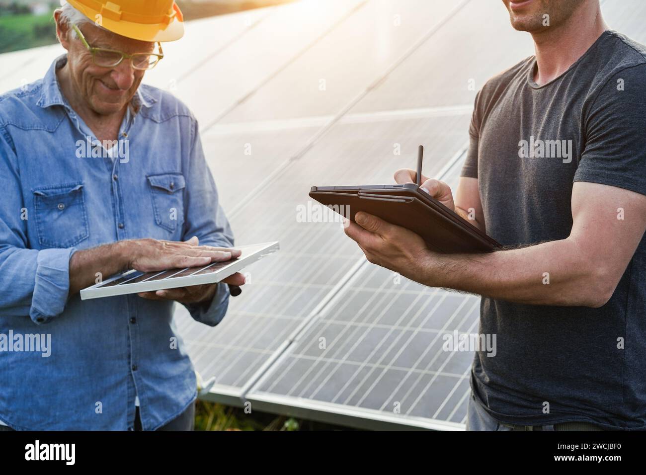 Ingegneri multigenerazionali che lavorano all'esterno in una fabbrica di pannelli solari - fotovoltaico, energia verde rinnovabile e concetto ambientale - Focus principale su r Foto Stock