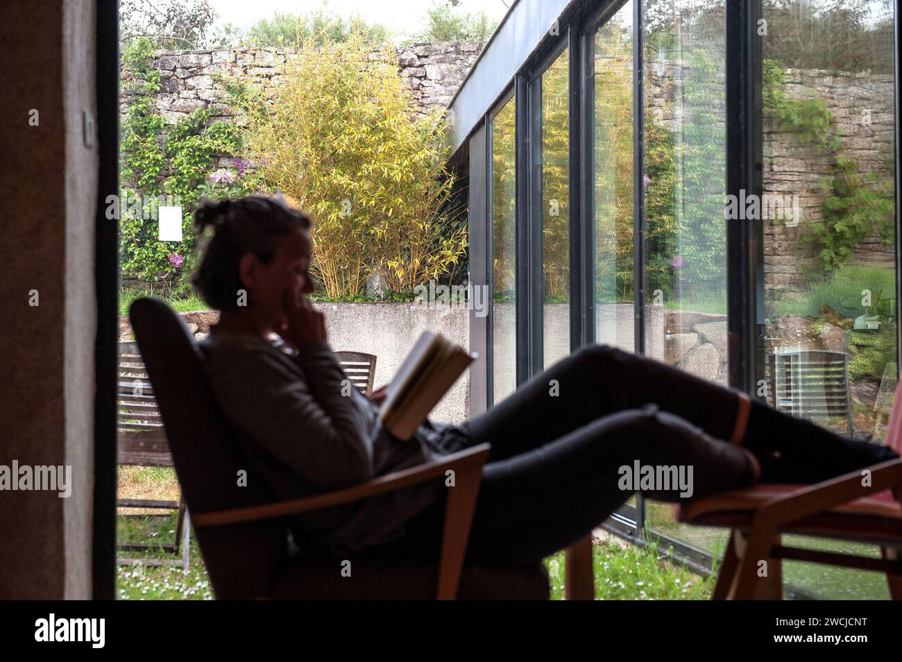 Donna che legge un libro in una casa moderna Foto Stock
