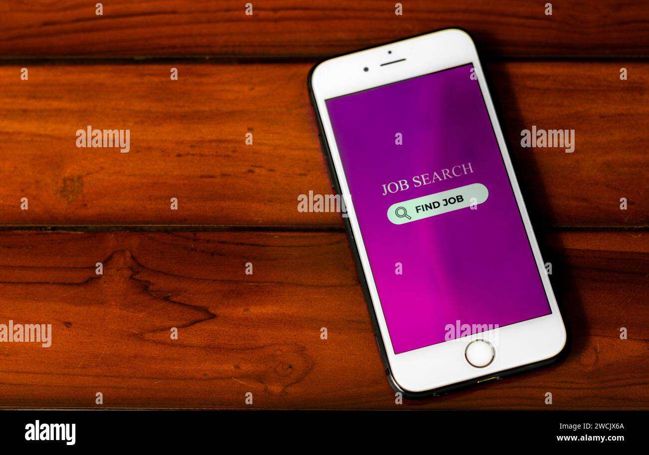 Concetto di ricerca di lavoro. Smartphone con app di ricerca del lavoro sullo schermo su sfondo in legno. Ricerca di opportunità di lavoro online. Foto Stock