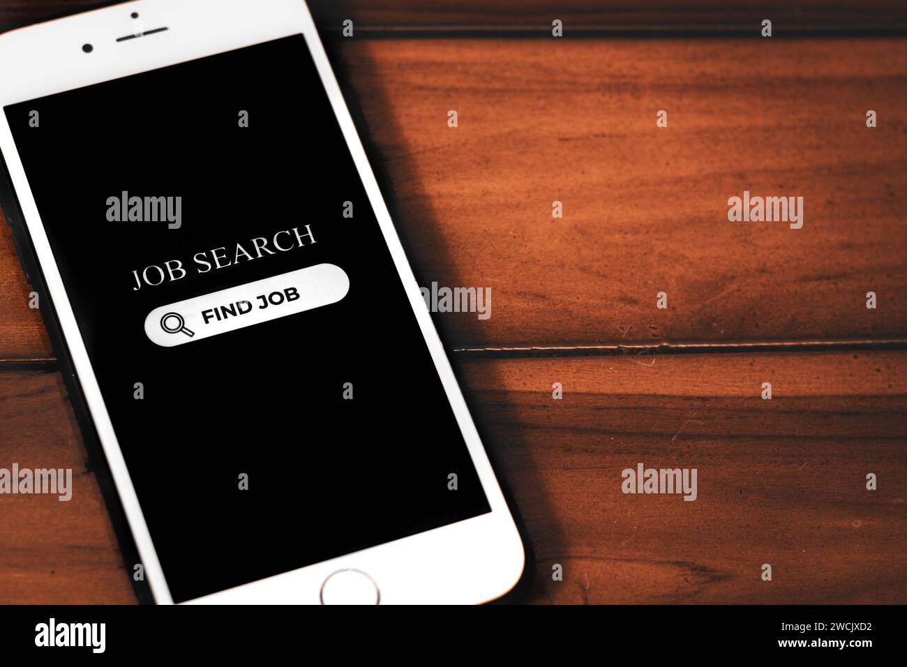 Concetto di ricerca di lavoro. Smartphone con app di ricerca del lavoro sullo schermo su sfondo in legno. Ricerca di opportunità di lavoro online. Foto Stock