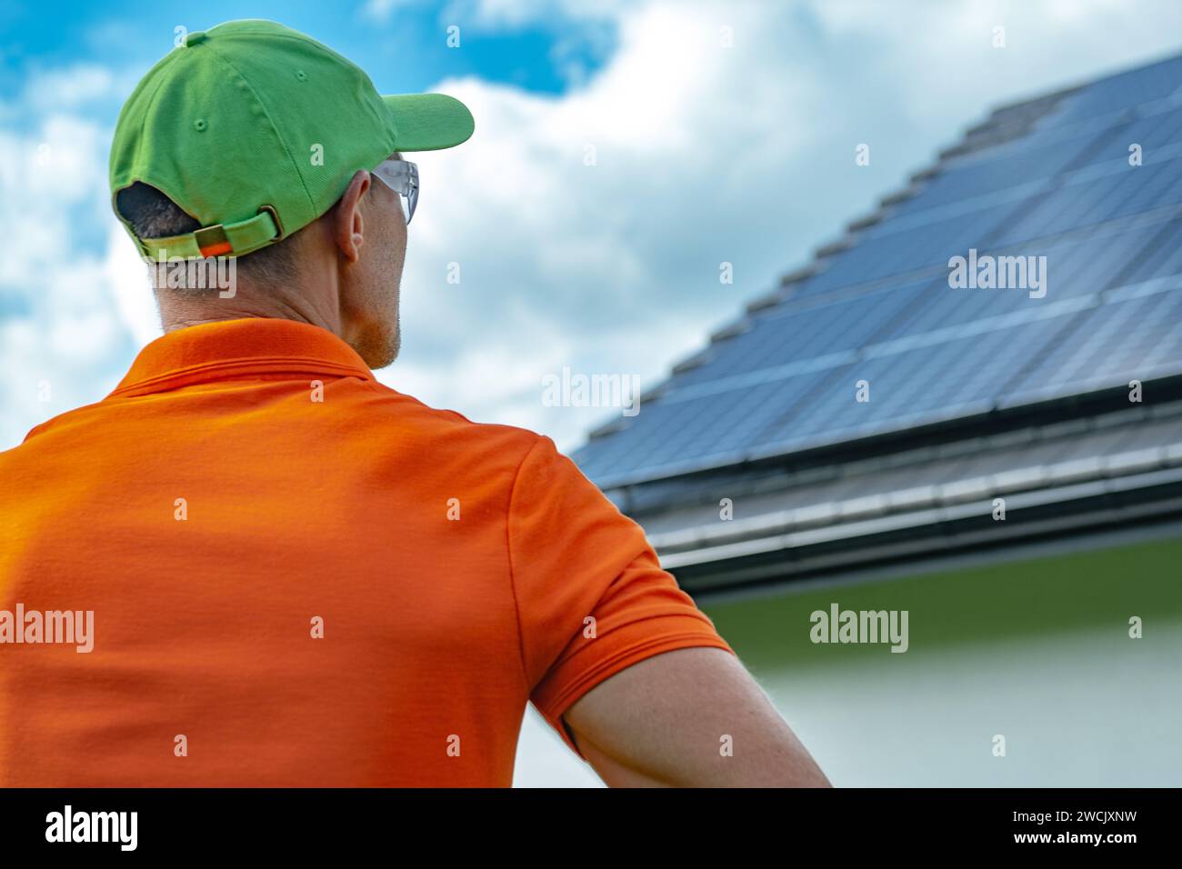 Installatore di pannelli solari professionale caucasico che guarda l'ultimo sguardo finale su un sistema fotovoltaico appena installato. Foto Stock