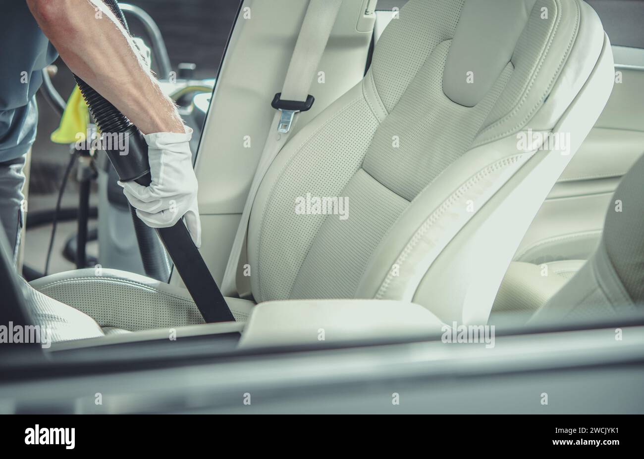 Un lavoratore della concessionaria caucasica che aspira gli interni moderni ed eleganti delle auto Foto Stock
