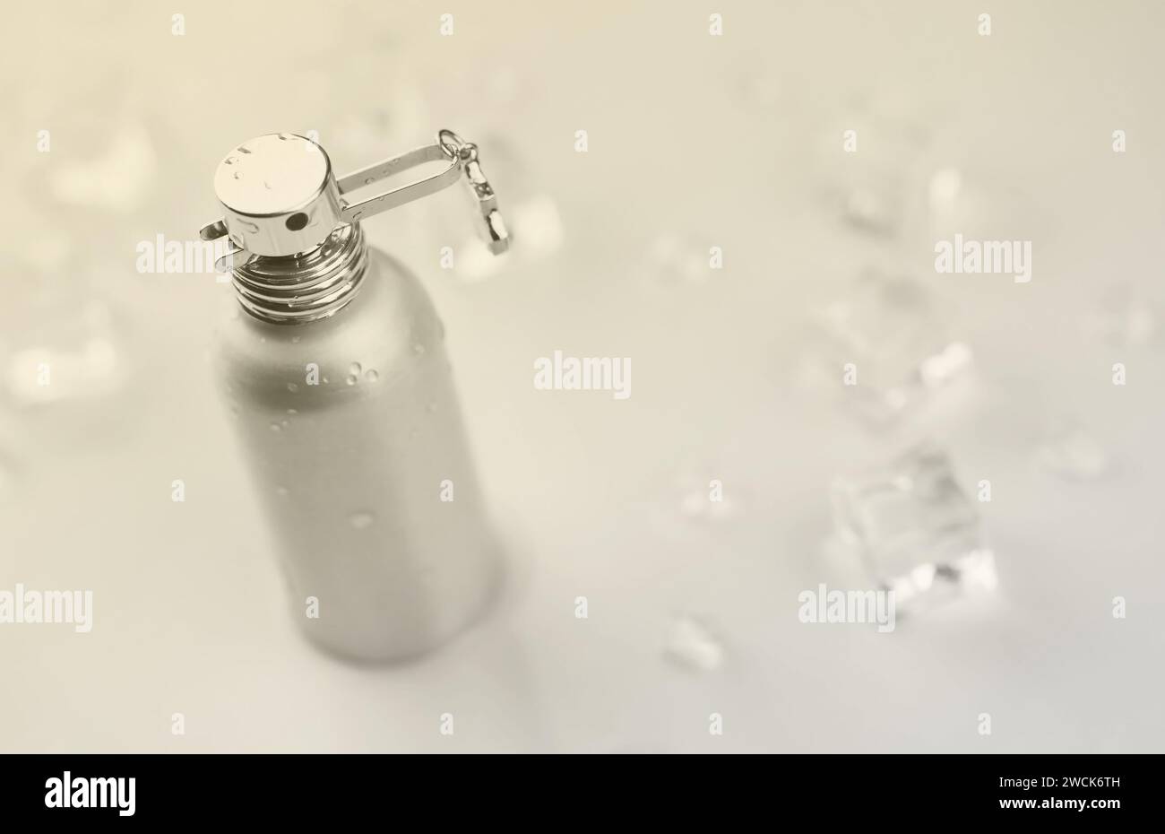 Bottiglia argentata di profumo femminile, fotografia oggettiva della bottiglia di profumo metallico in cubetti di ghiaccio e acqua su tavolo bianco. Vista dall'alto. Foto del prodotto mockup, concetto di freschezza e aroma Foto Stock
