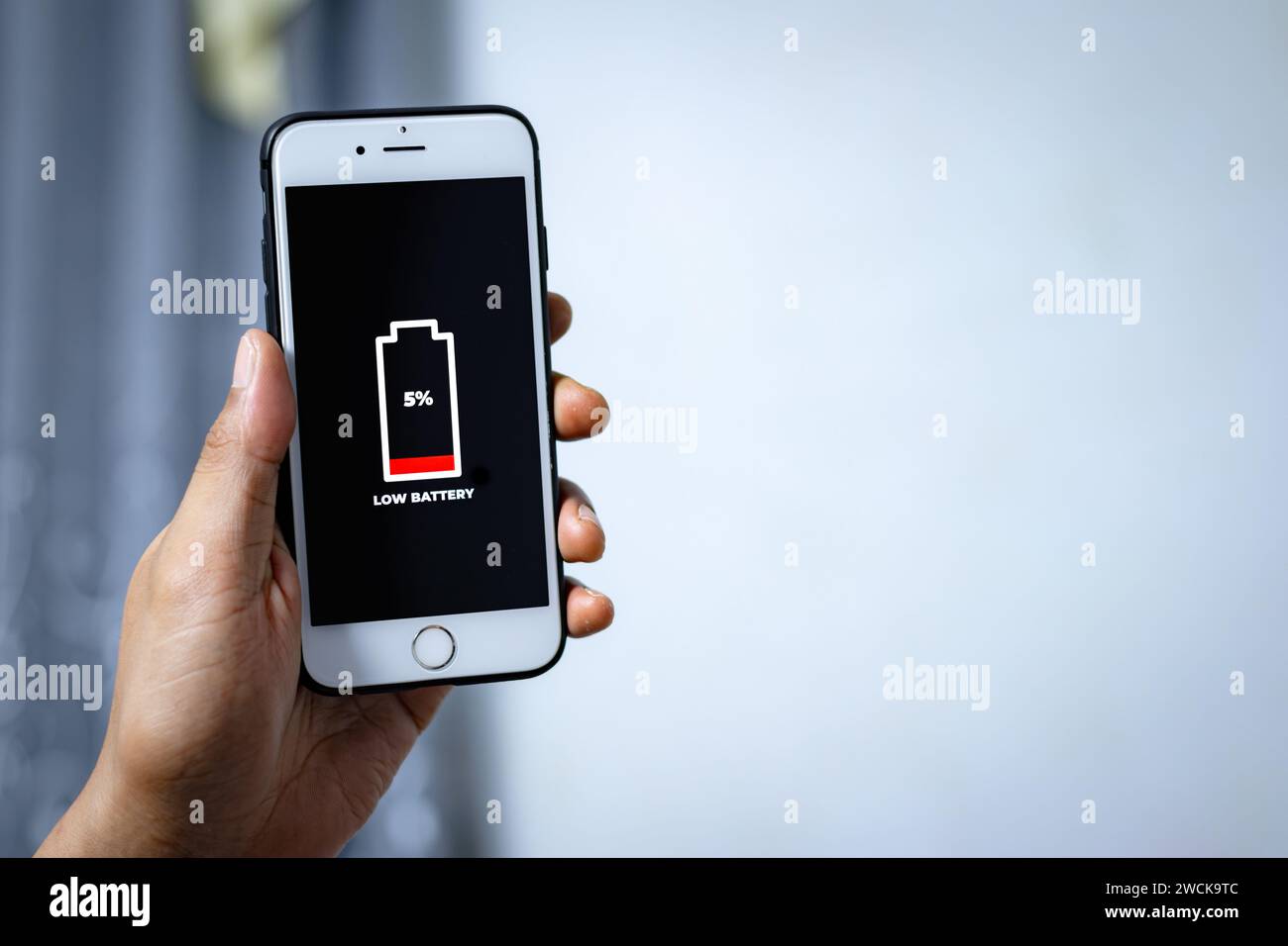 Problemi cellulari e concetti di energia. Mano maschile che regge uno smartphone con l'icona di batteria scarica sullo schermo. Foto Stock