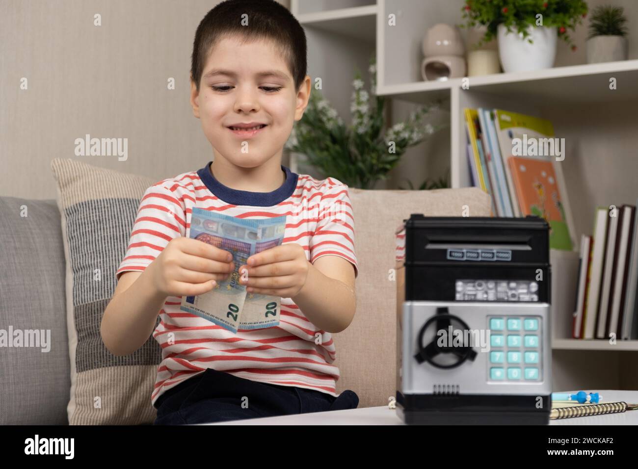 Un bambino sta risparmiando denaro, tenendo in mano le banconote in euro. Alfabetizzazione finanziaria per i bambini. Foto Stock