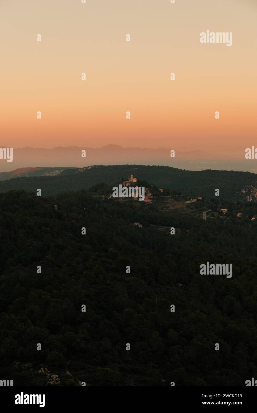 Il tramonto proietta un caldo bagliore sulle maestose cime delle montagne e sugli alberi circostanti Foto Stock