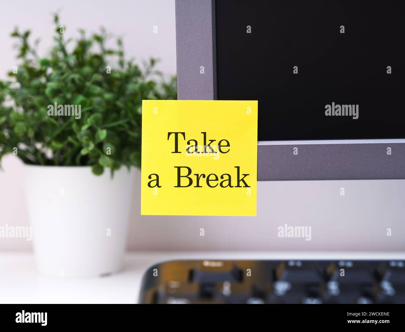 Una nota di carta gialla con le parole prende una pausa attaccata a un monitor in un ufficio. Foto Stock