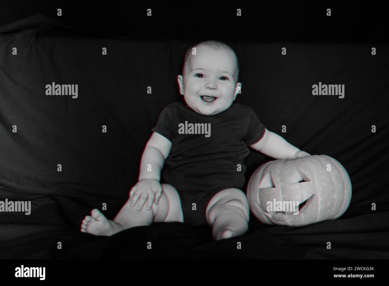 Un bambino felice che ride con la zucca di Halloween Jack su sfondo scuro. Effetto glitch realtà virtuale 3D. Foto Stock