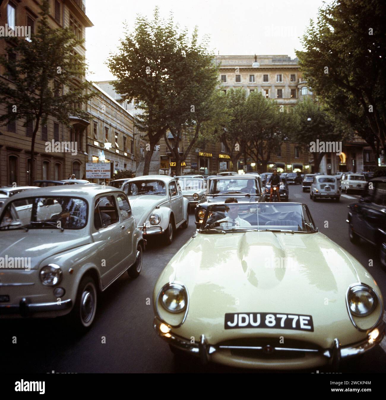Jaguar e-TYPE 1967, JDU877E, nel "West End" di Roma, durante l'ora di punta, circondato dal traffico e dai frequentatori del teatro per vedere Napoli notte e giorno. Foto Stock
