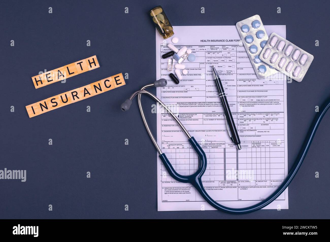 Modulo di assicurazione sanitaria con stetoscopio e pillole sul tavolo. Assicurazione medica, rischio sanitario, pagare per il concetto di assistenza sanitaria. Foto Stock